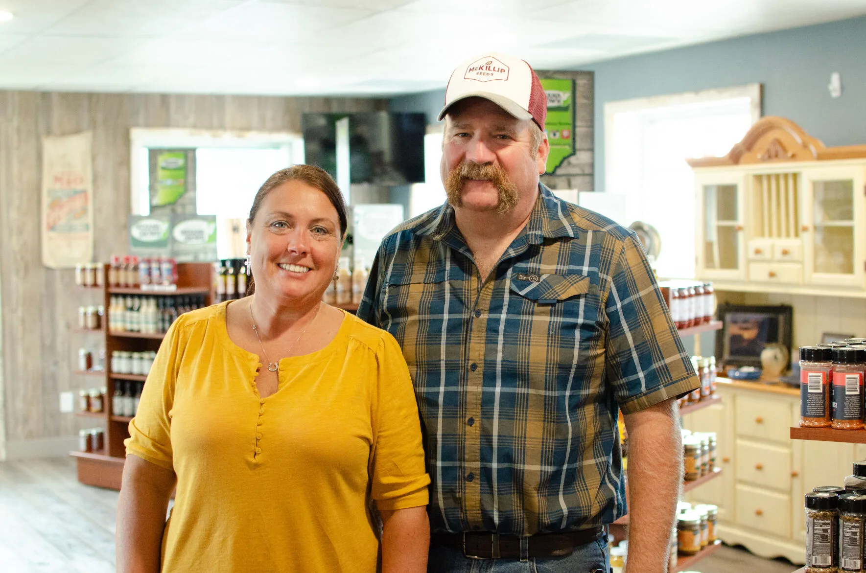 Rachel Boyer wears a yellow shirt and smiles next to Mark Boyer, who is wearing. hat and a yellow and blue flannel shirt.